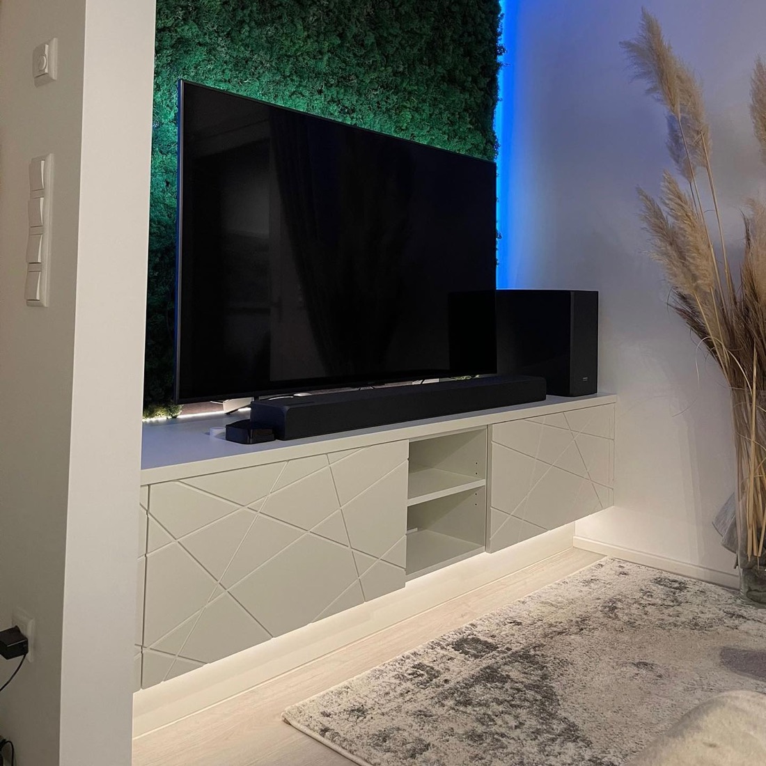 Weißes TV-Lowboard mit gefrästen Fronten vor Mooswand